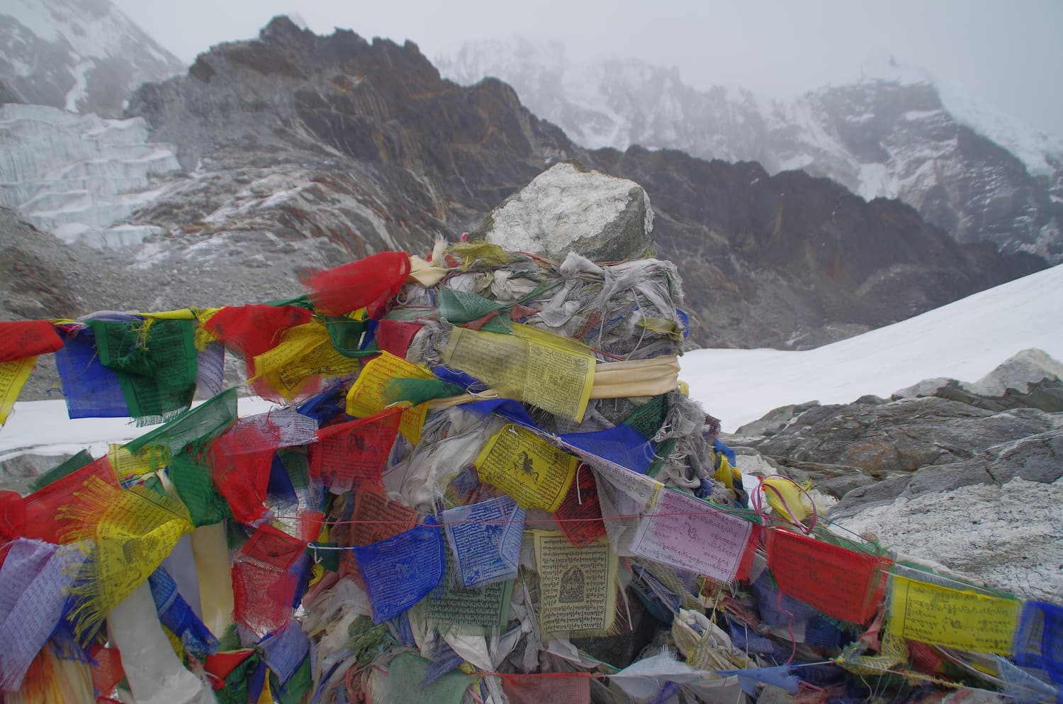 Colourful prayer flags on the rocky, snowy crest of the Cho La pass